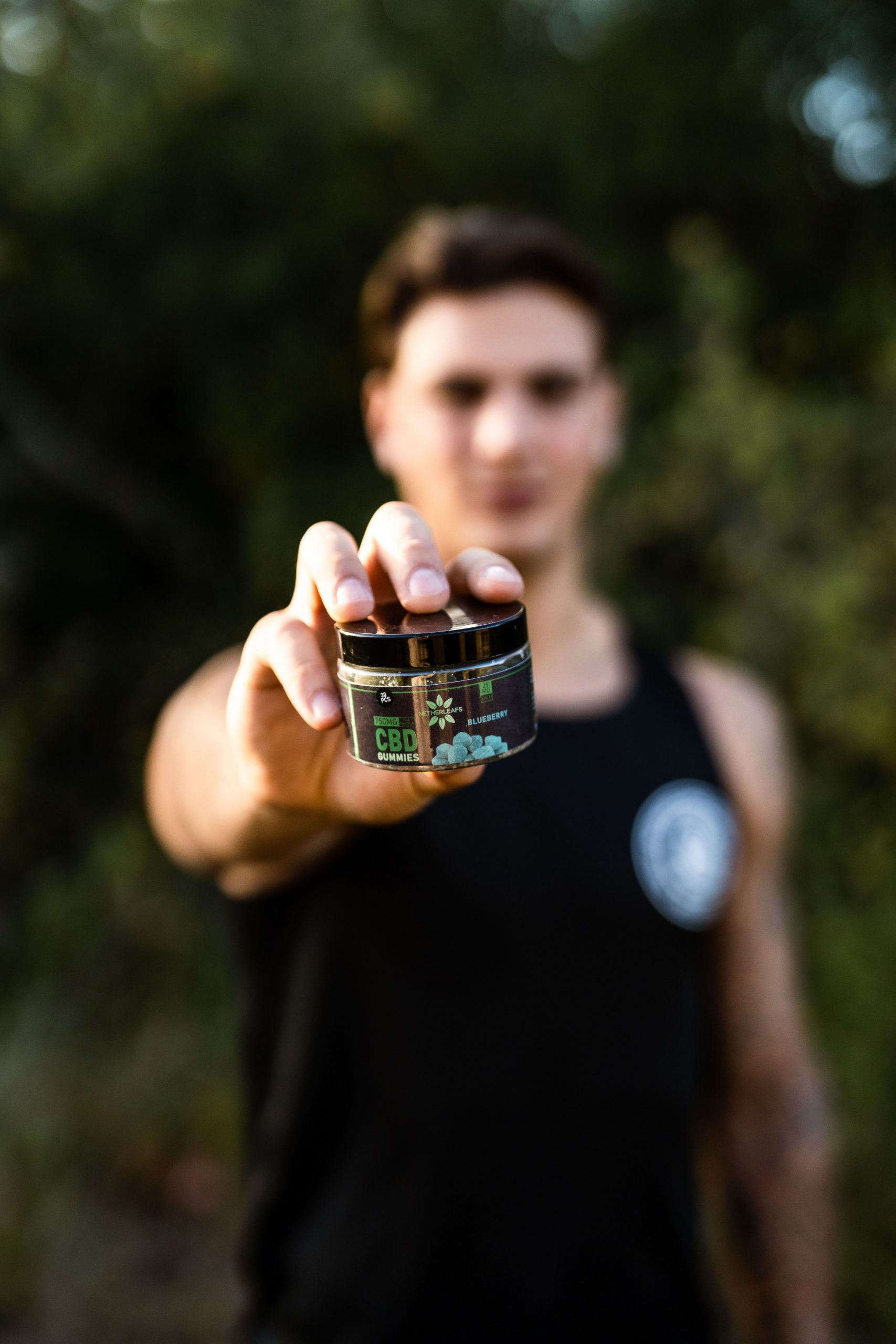 Man holding a pack of CBD gummies in front of him, showcasing Netherleafs' premium CBD products.